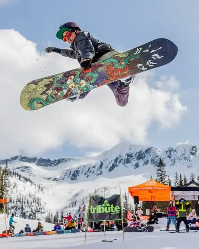 Pete Moss, co-founder of REWILD Mushrooms, snowboarding mid-air above a mountain event